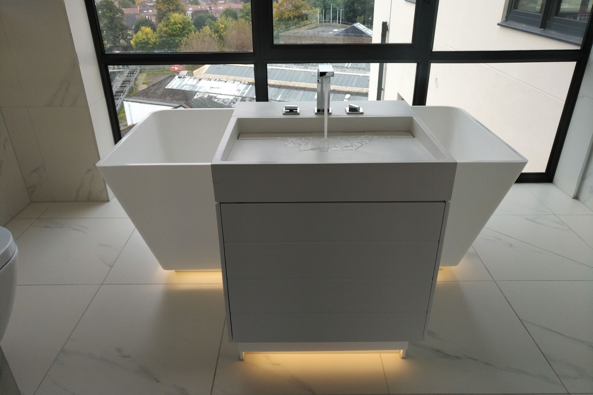 Sculptural freestanding basin against black-framed glazing