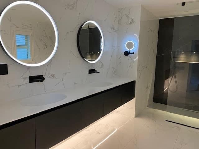 Marble bathroom with round illuminated mirrors